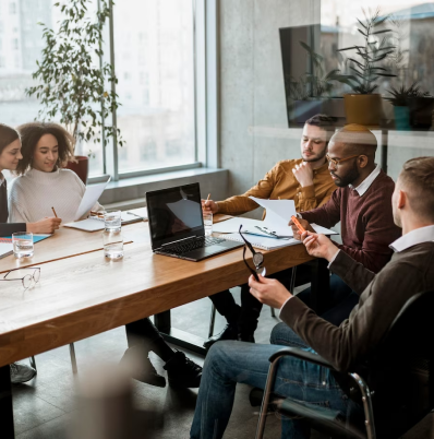 Grupo de pessooas discutindo em volta de uma mesa de reunião.